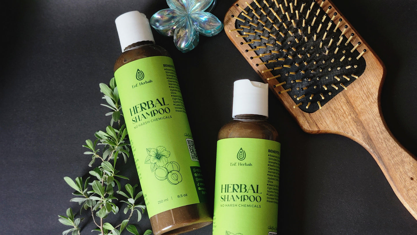 Two bottles of herbal shampoo with a wooden brush on a dark background
